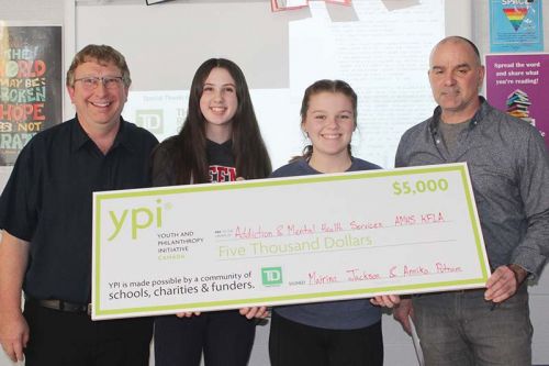 Annika Putnam and Mairina Jackson with teacher Randy McVety and principal James McDonald showint the $5,000 cheque that will be going to Addiction & Mental Health Services KFLA after Jackson and Putnam’s winning presentation. Photo/Craig Bakay